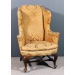 An 18th Century walnut wing back armchair with out turned arms, upholstered in old gold brocade,