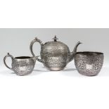 A late Victorian silver spherical three piece tea service, the whole embossed with Near Eastern