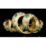 A modern gold coloured metal mounted emerald and diamond set brooch of scrolling design, the face