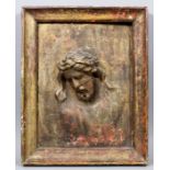 A 19th Century Continental wood panel carved with the head and chest of the crucified Christ, his