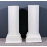 A pair of white painted papier mache short columns with fluted sides, on white painted square plinth