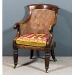 A George IV mahogany framed Bergere armchair with curved crest rail to tub-shaped back, on scroll