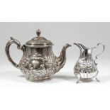 A Victorian silver teapot and matching milk jug, the bulbous bodies embossed with C-scroll and