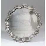A George V silver circular salver with shaped and moulded rim, on three scroll supports, 9.75ins