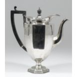 A George V silver coffee pot of octagonal panelled form, with ebonised finial and angular loop