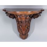 A Victorian walnut bow fronted clock or wall bracket with moulded edge, supported on bold carved