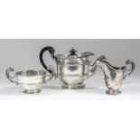 A George V silver circular three piece tea service with moulded rims and girdles and high C-scroll