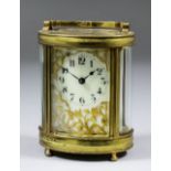 An early 20th Century French oval carriage timepiece, the cream enamel dial with Arabic numerals,