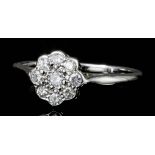 A modern 18ct white gold all diamond set flowerhead pattern ring, the face pave set with nine