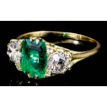 A modern gold coloured metal mounted emerald and diamond three stone ring, the central oval cut