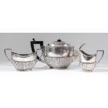 A George V silver three piece tea service of Georgian design, with oval partly reeded bodies