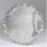 An Edward VIII silver circular salver with shaped and moulded rim, on four scroll supports, 16.25ins