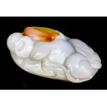 A Chinese carved viened agate figure of a Hotei reclining on a leaf, the stone with brown