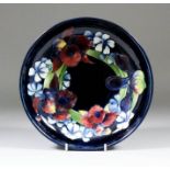 A Moorcroft shallow pottery bowl, tubelined and decorated in colours with "Orchid and Gillyflower"