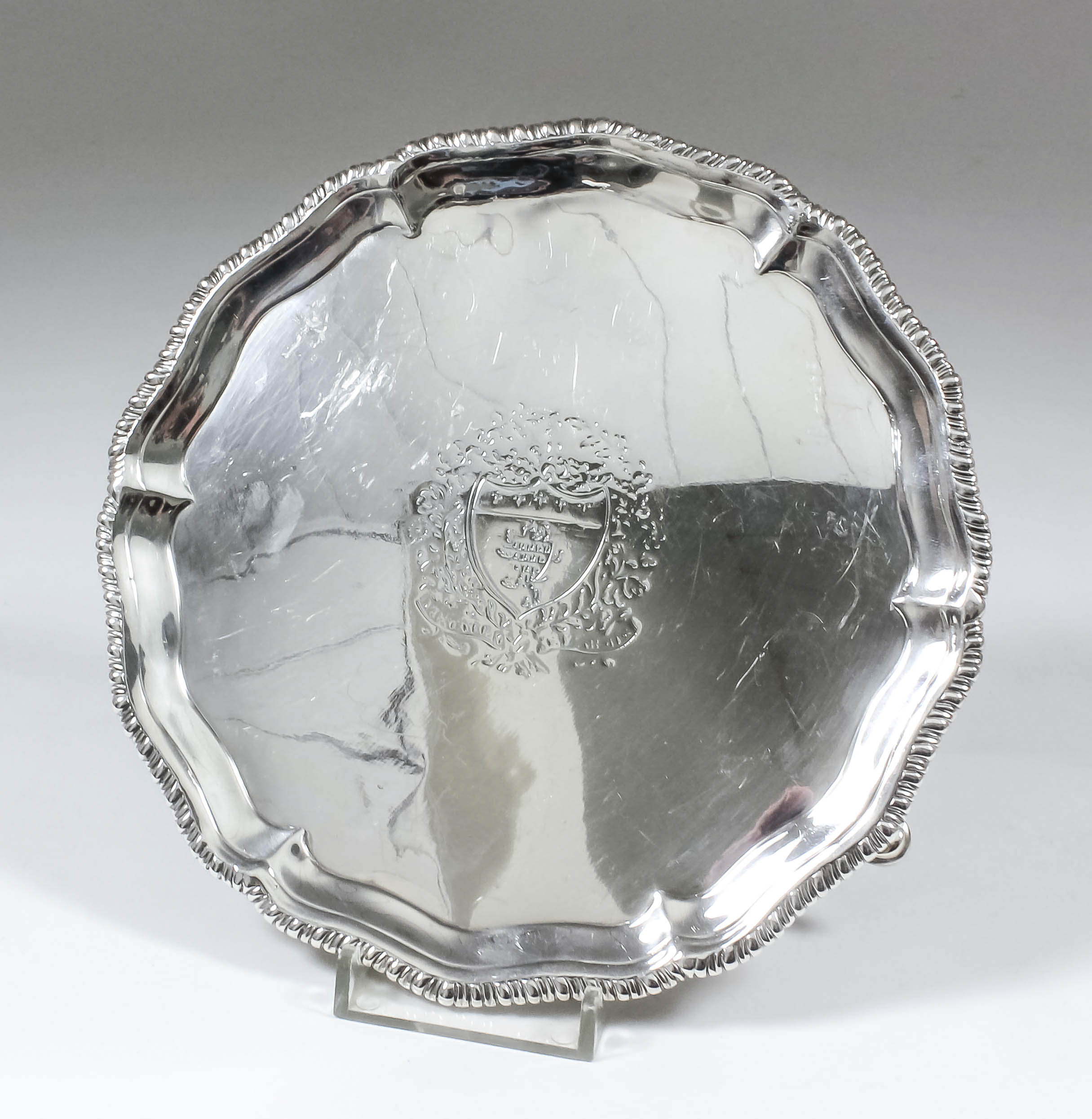 A George III silver circular waiter, the shaped and moulded rim with gadroon mounts, on three scroll