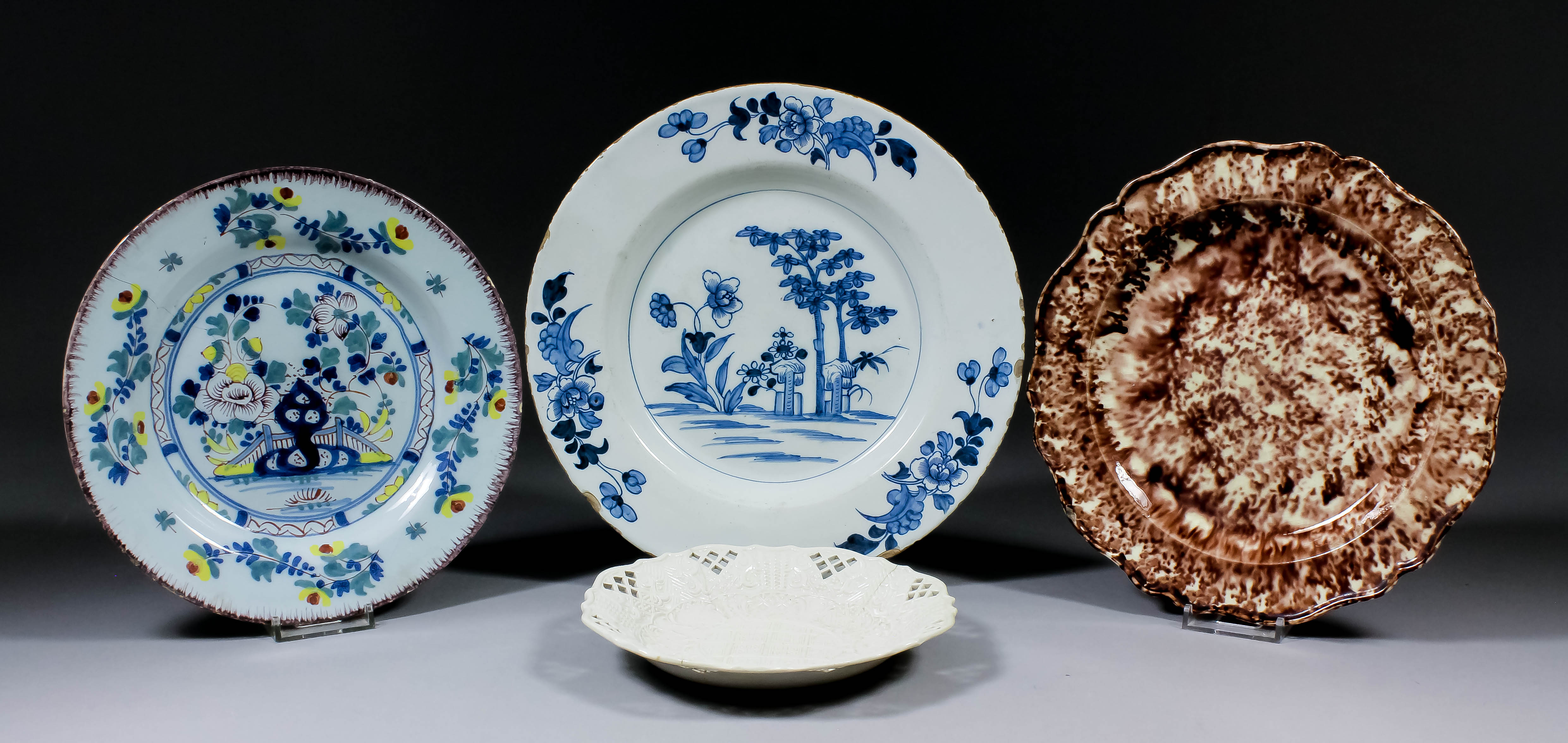 Four 18th Century English pottery plates, comprising - Delft painted in colours with fence and
