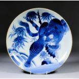 A Japanese porcelain blue and white charger painted with a stalking tiger amongst bamboo, 13.5ins (