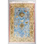 A Qum rug woven in fawn, ivory and pale blue with various animals, birds and flowering trees, on a