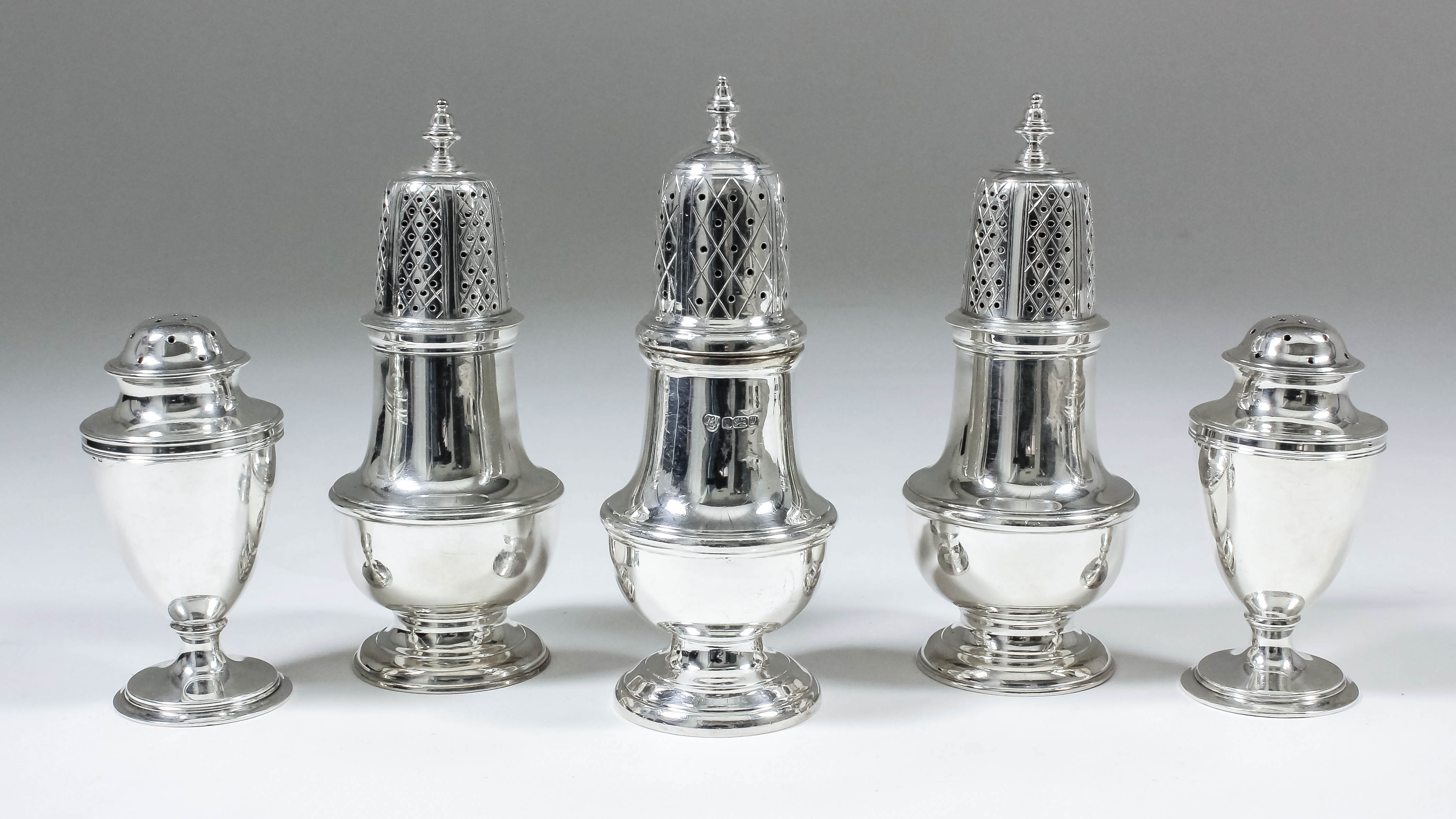 A pair of Elizabeth II silver pepper pots, the pierced domed covers with turned finials, with