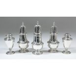 A pair of Elizabeth II silver pepper pots, the pierced domed covers with turned finials, with