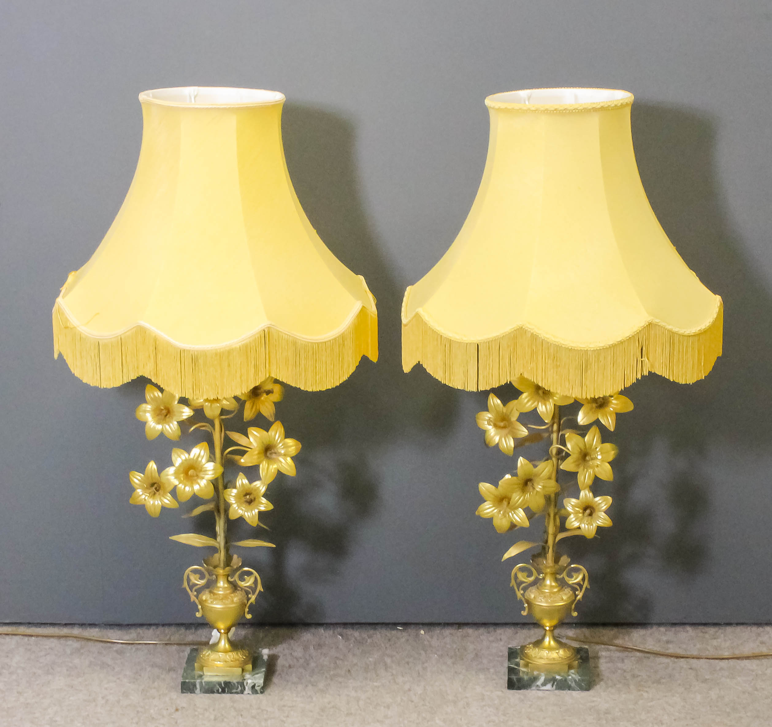 A pair of French gilt brass electric table lamps in the form of vases of flowers, on green and white