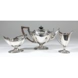 A late Victorian silver oval three piece tea service with shaped and reeded rims, angular loop