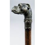 An early 20th Century patinated brass mounted figural walking case, the handle cast in the form of a