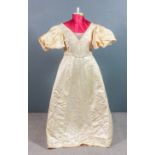 A 1950s oyster satin beaded wedding dress, the bodice and central panel worked with floral ornament,