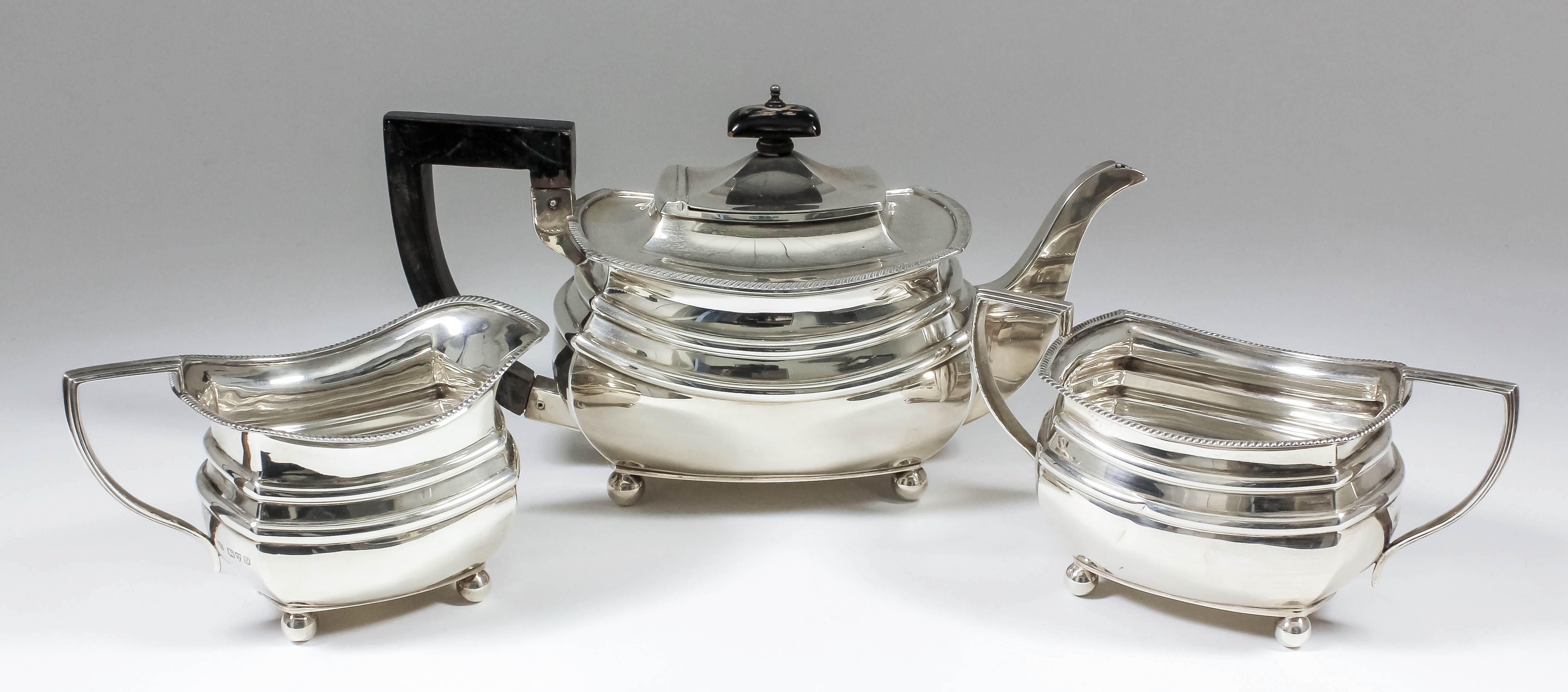 A George V silver rectangular three piece tea service with gadroon mounts and moulded bodies,