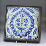 A 17th Century Iznik pottery tile painted in underglaze enamels with a vase of flowers within a