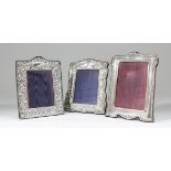 Three Elizabeth II silver rectangular photograph frames, one of shaped outline, embossed with vacant