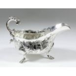 A Victorian silver oval sauce boat with shaped rim, embossed with C-scroll floral and leaf ornament,