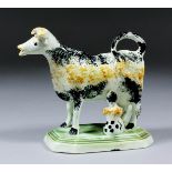 A 19th Century English pearlware cow creamer with milkmaid, sponged in black and yellow, on