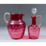 A Victorian cranberry glass water jug with dimpled body, 7.5ins high, and a similar ewer and