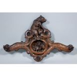 A late 19th Century "Black Forest" carved wood wall mounted coat hook, the shaped and pierced back