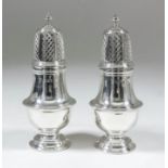 A pair of George V silver pepper pots, the domed covers with turned finials, with moulded girdles to