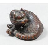 A Japanese carved hardwood Netsuke of a tiger, 1.5ins (3.8cm) x 1ins (2.55cm) high, signed