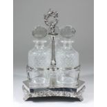 A plated three bottle wine cruet with central scroll cast loop handle, on reeded uprights, the