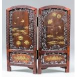 A fine Japanese hardwood and shibayama two fold table screen, finely pierced and carved with