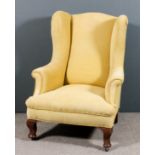 A 1920s wing back easy chair of "Georgian" design, upholstered in gold cloth and corded, on short