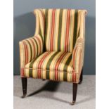 An Edwardian wing back easy chair upholstered in striped cloth, on square tapered front legs and