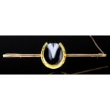 A late Victorian 9ct gold mounted horseshoe pattern bar brooch, set to the centre with 14ct gold