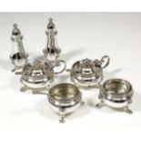 A George V silver six piece condiment set with moulded rims and on scroll supports with hoof pattern