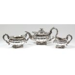 A George IV silver circular three piece tea service with oval bead mounts, cast floral finial,