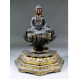 An Eastern lacquered and gilded wood Buddha, his hands forming the gesture of meditation and