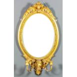 A pair of 19th Century gilt framed oval girandoles with oval boss and leaf scroll carved crestings