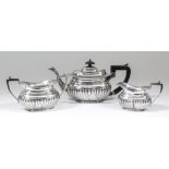 A George V silver oval three piece tea service, with moulded rims and part reeded bulbous bodies,