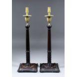 A pair of George III mahogany and brass pillar candlesticks with spiral fluted sconces, fluted and