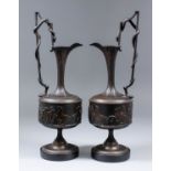 A pair of brown patinated bronze ewers after the antique with slender fluted necks, circular