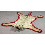 An Indian tiger skin rug, the mounted head with open mouth showing teeth and with glass eyes, the